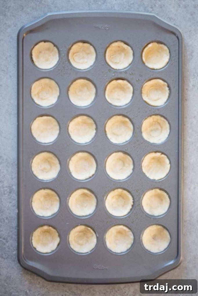 Pressing pecan tassie dough into the mini muffin tin cavities