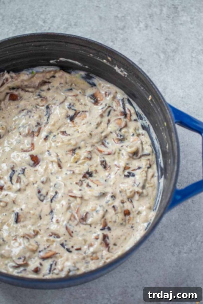 A close-up shot of rich, creamy homemade cream of mushroom soup simmering in a skillet, ready for green beans.