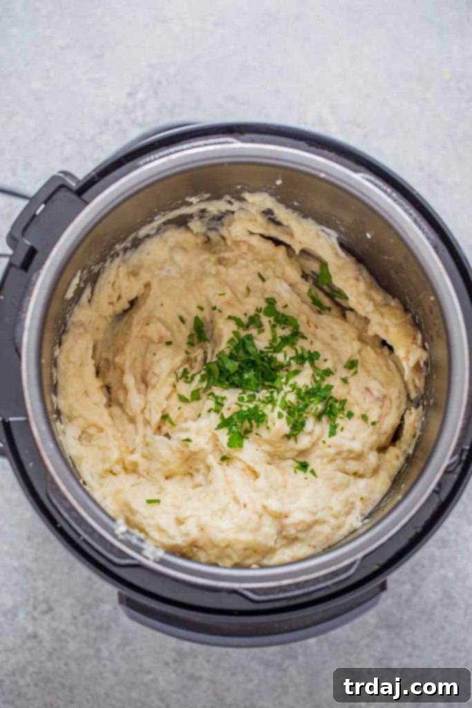 Instant Pot filled with perfectly cooked potatoes, cream cheese, butter, horseradish, garlic, and parsley, ready for mashing.