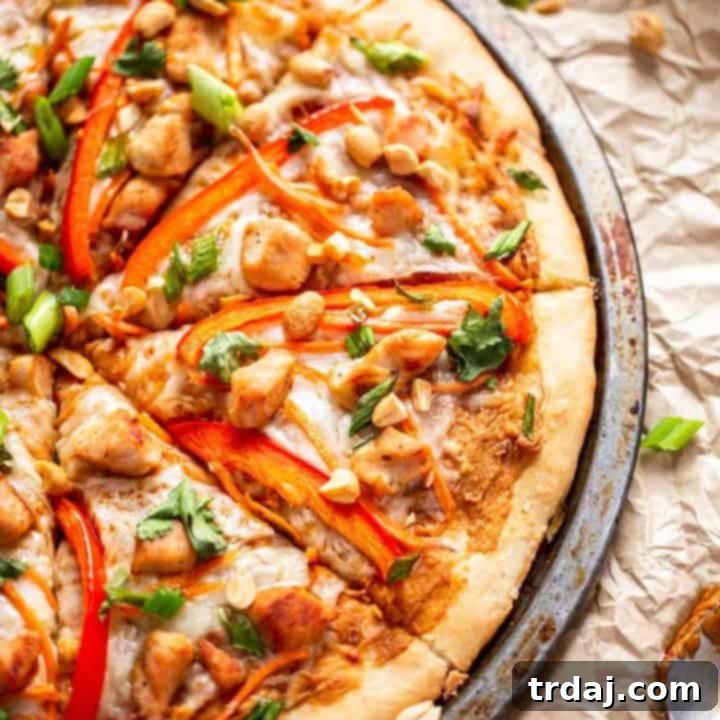 Top-down view of a whole Thai Chicken Pizza, freshly baked and garnished with cilantro and peanuts.