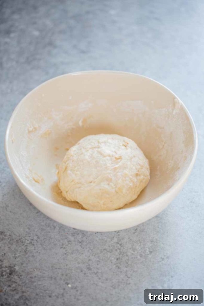 A smooth ball of homemade pizza dough resting on a floured surface, ready to be rolled out.