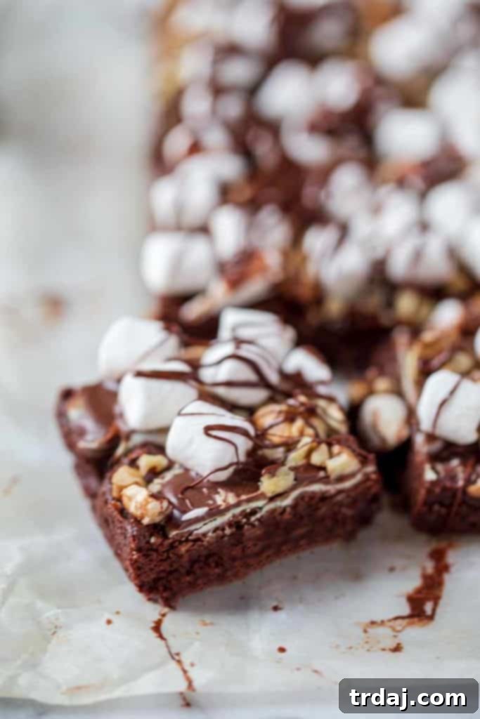 A single piece of Mocha Mint Mississippi Mud Brownie, showcasing its rich layers of chocolate, mint, pecans, and marshmallows, ready to be enjoyed.