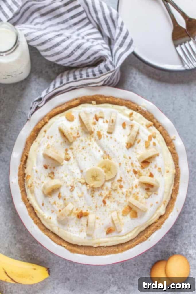 Whole No Bake Banana Cream Pie with Pecan Crust, topped with fresh banana slices and pecan pieces