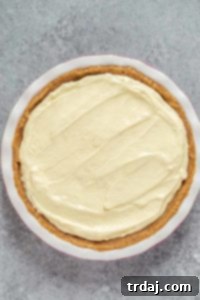 Layers of bananas, pudding, and whipped topping in a pie pan, showing the progression of the pie assembly