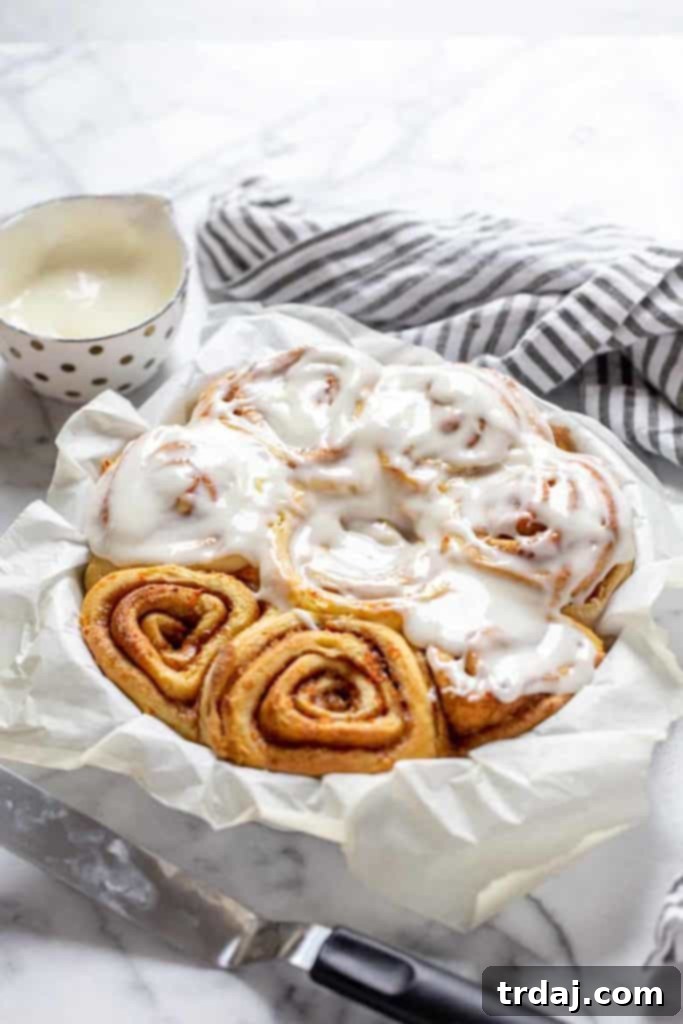 Carrot Cake Cinnamon Rolls with Cream Cheese Icing, freshly baked and partially drizzled in a baking pan