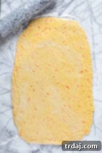 Carrot cake cinnamon roll dough rolled out on a floured surface