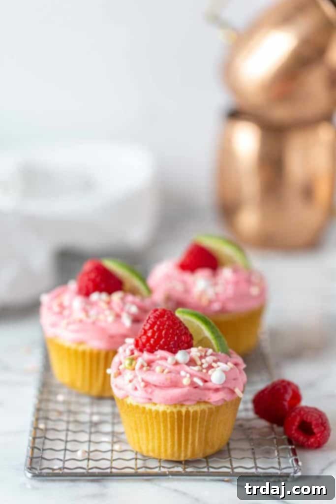 3 Raspberry Moscow Mule Cupcakes lined up with fresh raspberries