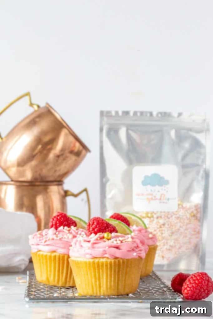 Raspberry Moscow Mule Cupcakes with copper mugs and sprinkles in the background