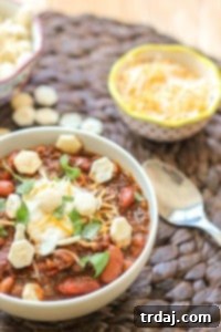 Chorizo Chili with Jalapeño Cornbread Waffles is perfect for game day, a chilly fall night or neighborhood potluck. This beefy flavored packed chili gets a slight kick from the spicy chorizo sausage. Served on top of cornbread waffles, dolloped with cheese and cilantro, and you've got yourself a well rounded meal! | Strawberry Blondie Kitchen