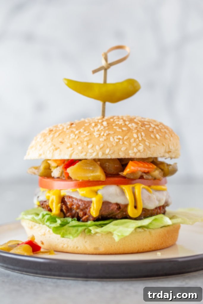 Signature Chicago Beyond Burger 3 A close-up view of a perfectly assembled Chicago Style Beyond Burger, featuring a juicy plant-based patty layered with melted provolone cheese, vibrant yellow mustard, crisp lettuce, ripe tomato, and tangy giardiniera, all on a sesame seed bun.