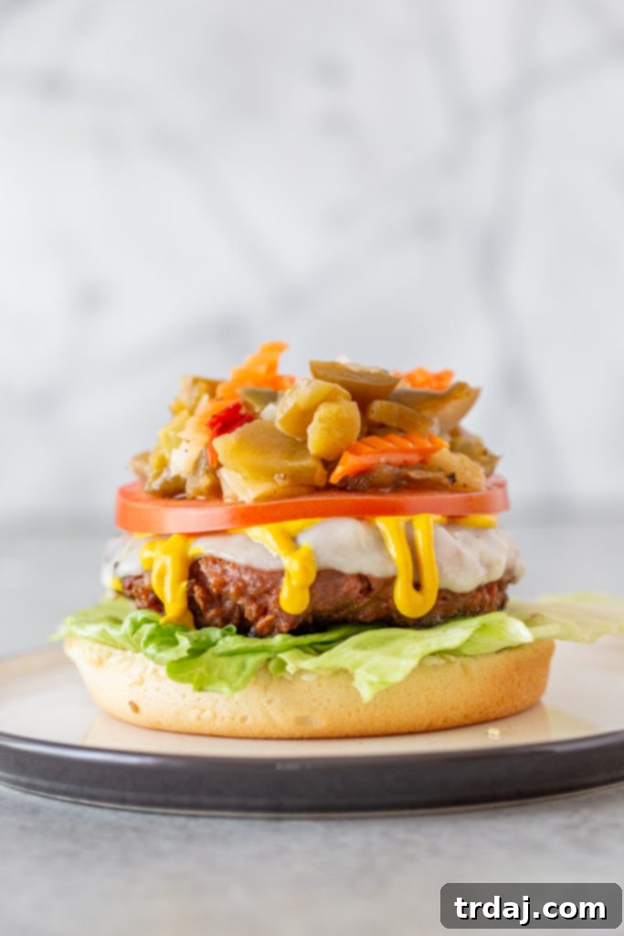 Signature Chicago Beyond Burger 7 A perfectly assembled Chicago Style Beyond Burger showcasing a plant-based patty, melted provolone cheese, yellow mustard, lettuce, tomato, and giardiniera on a seeded bun, ready to be enjoyed.