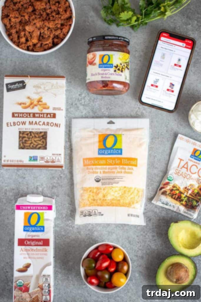 A vibrant flat lay of ingredients for healthy one pan taco pasta, including a packet of taco seasoning, whole wheat elbow macaroni, a jar of black bean and corn salsa, a carton of unsweetened almond milk, O Organics plant-based crumbles, and a block of Mexican style cheese