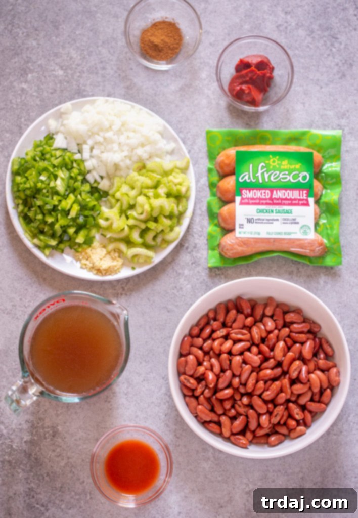 Flavorful and rich, with andouille sausage and hearty vegetables, this One Pan Easy Red Beans and Rice is pure comfort food and on the table in less than 30 minutes! A vibrant flat lay showcasing all the fresh and pantry ingredients required for making a delicious batch of red beans and rice, including bell pepper, onion, celery, garlic, chicken sausage, and canned beans.