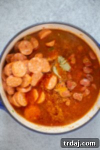 Effortless Red Beans and Rice 4 A hearty combination of green bell pepper, onion, celery, garlic, tomato paste, Cajun seasoning, al fresco andouille chicken sausage, and red kidney beans are simmering together in a pot, ready to create a comforting red beans and rice dish.