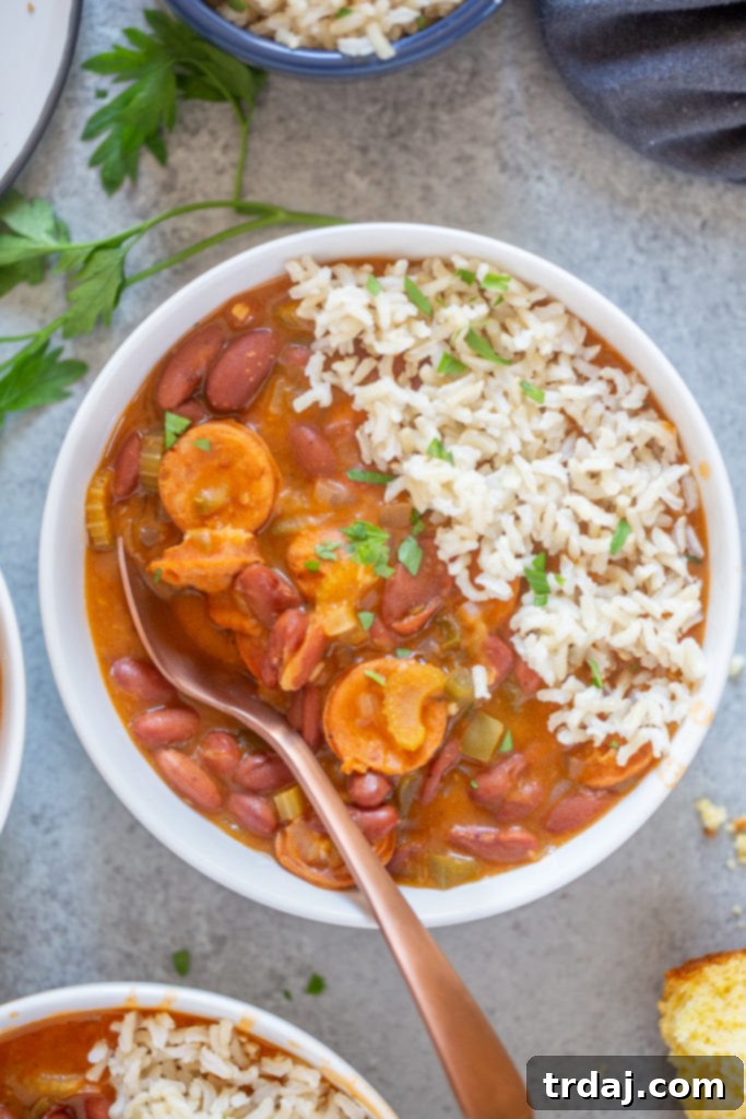 Flavorful and rich, with andouille sausage and hearty vegetables, this One Pan Easy Red Beans and Rice is pure comfort food and on the table in less than 30 minutes! A tantalizing close-up of a generous serving of red beans and rice in a rustic bowl, with fluffy rice layered over the rich, saucy beans, ready to be savored.