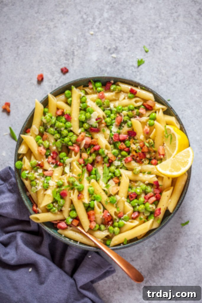 A close-up shot of Crispy Pancetta and Sweet Pea Ziti in a bowl, garnished with fresh herbs.