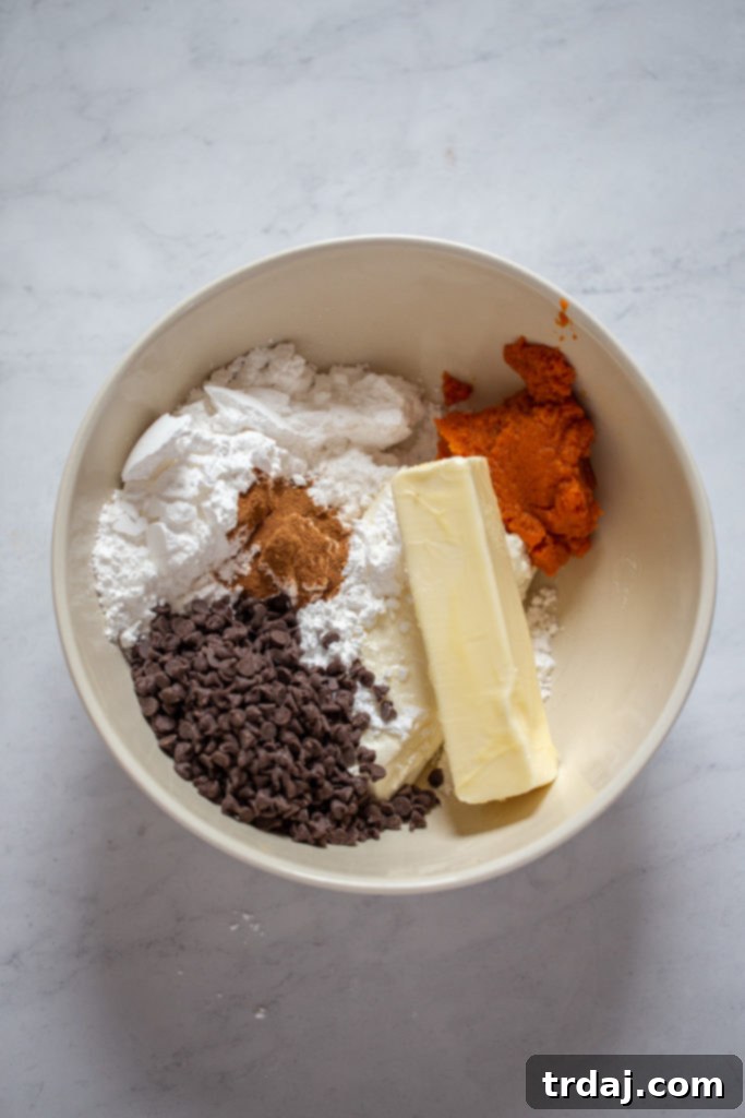 Mixing cream cheese, butter, pumpkin puree, and pumpkin pie spice