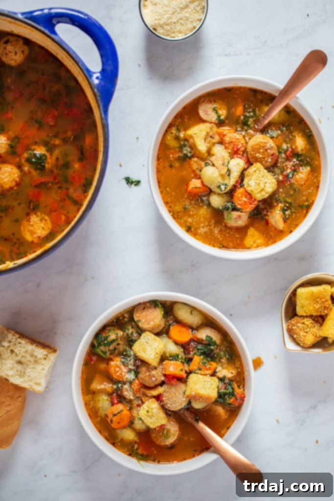 Two bowls of Italian Chicken Gnocchi Soup garnished with fresh herbs and a spoon