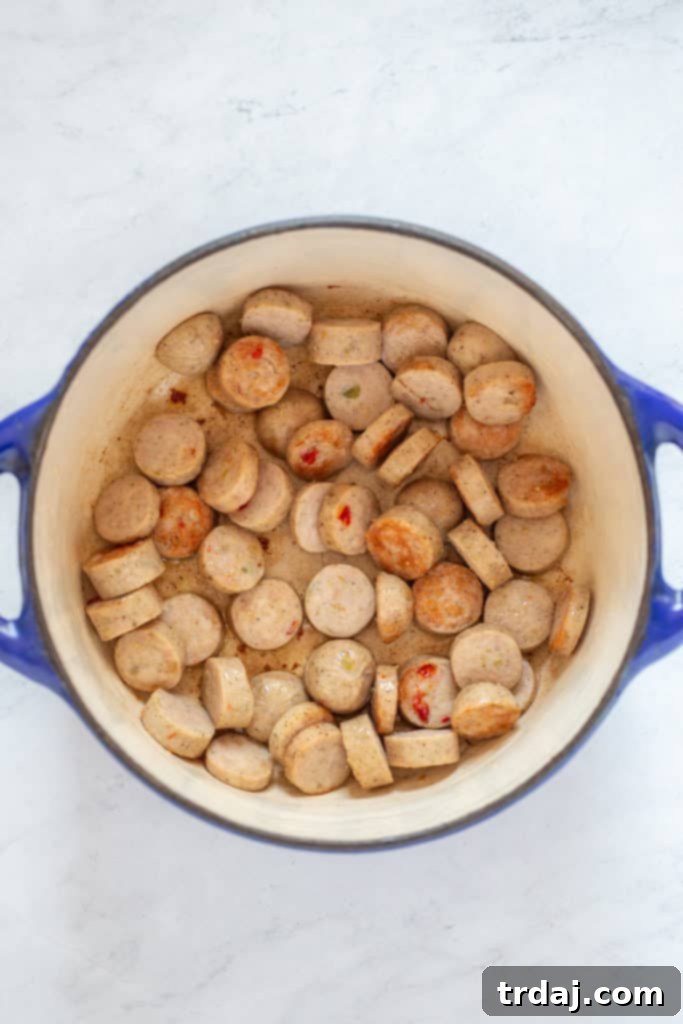 Sweet Italian chicken sausage browning in a large pot with olive oil