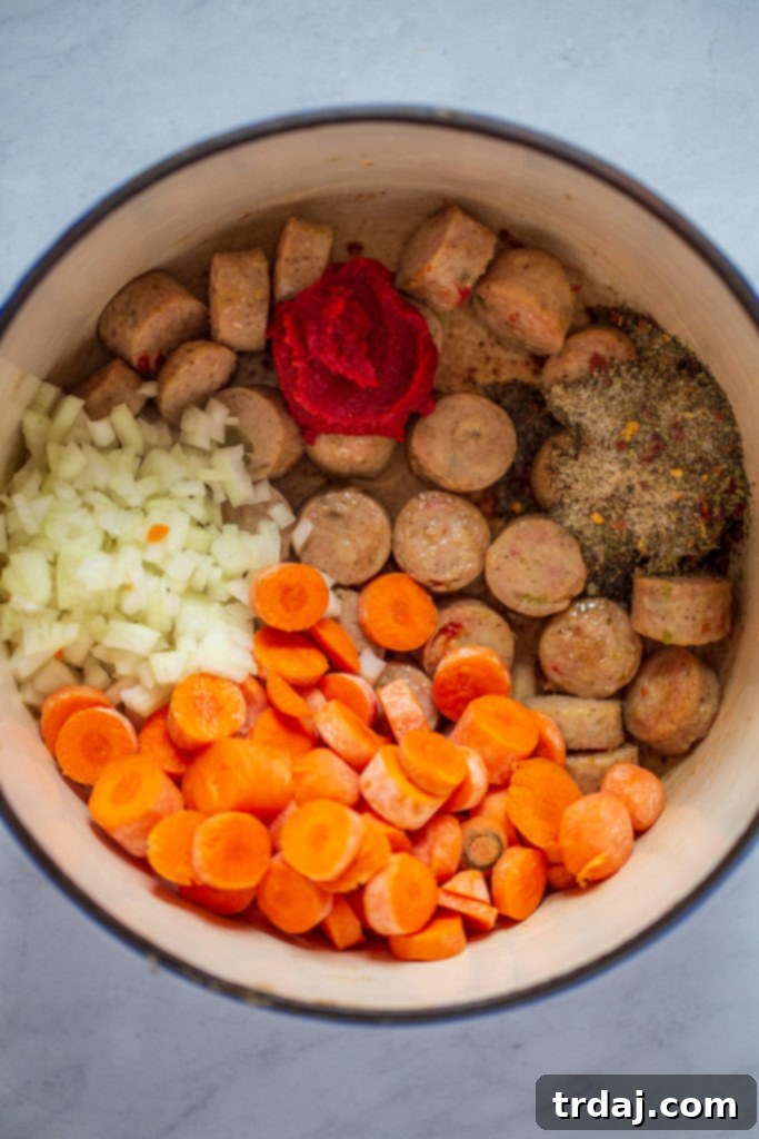 Italian chicken sausage cooking with softened onions, carrots, tomato paste, and spices