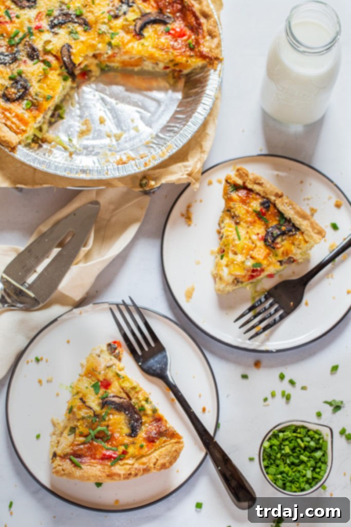 Slices of vegetable quiche on a plate with forks, showing the delicious layers and golden crust.