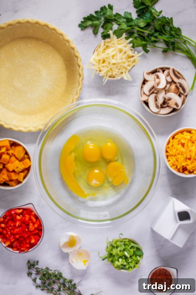 Assortment of fresh ingredients laid out for easy Vegetable Quiche preparation: eggs, vegetables, cheeses, and spices.