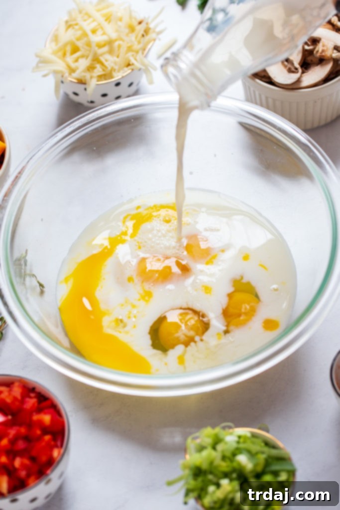 Mixing bowl with eggs, milk, salt, pepper, paprika, cayenne, cheeses, and leeks being combined for the quiche filling.