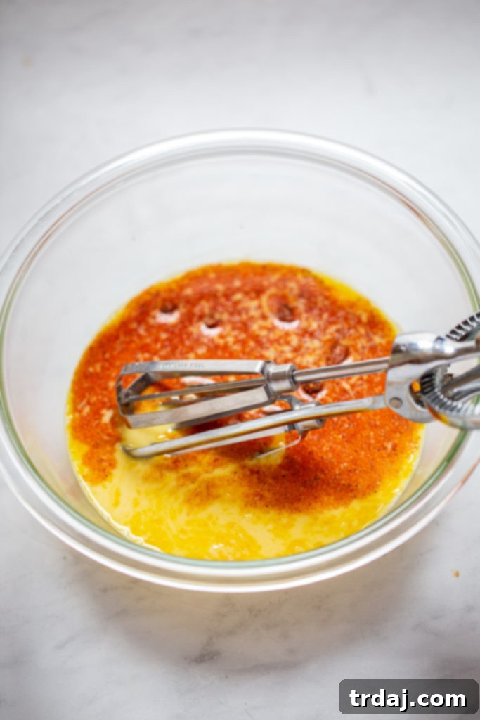 Pouring the red pepper and mushroom mixture into the bottom of a prepared pie crust for the quiche base.