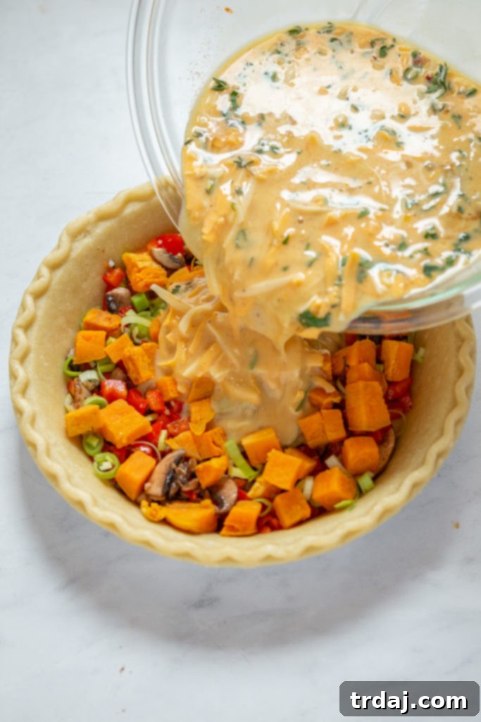 The egg and milk mixture, combined with vegetables, poured into the pie crust, ready for baking this vegetable quiche.
