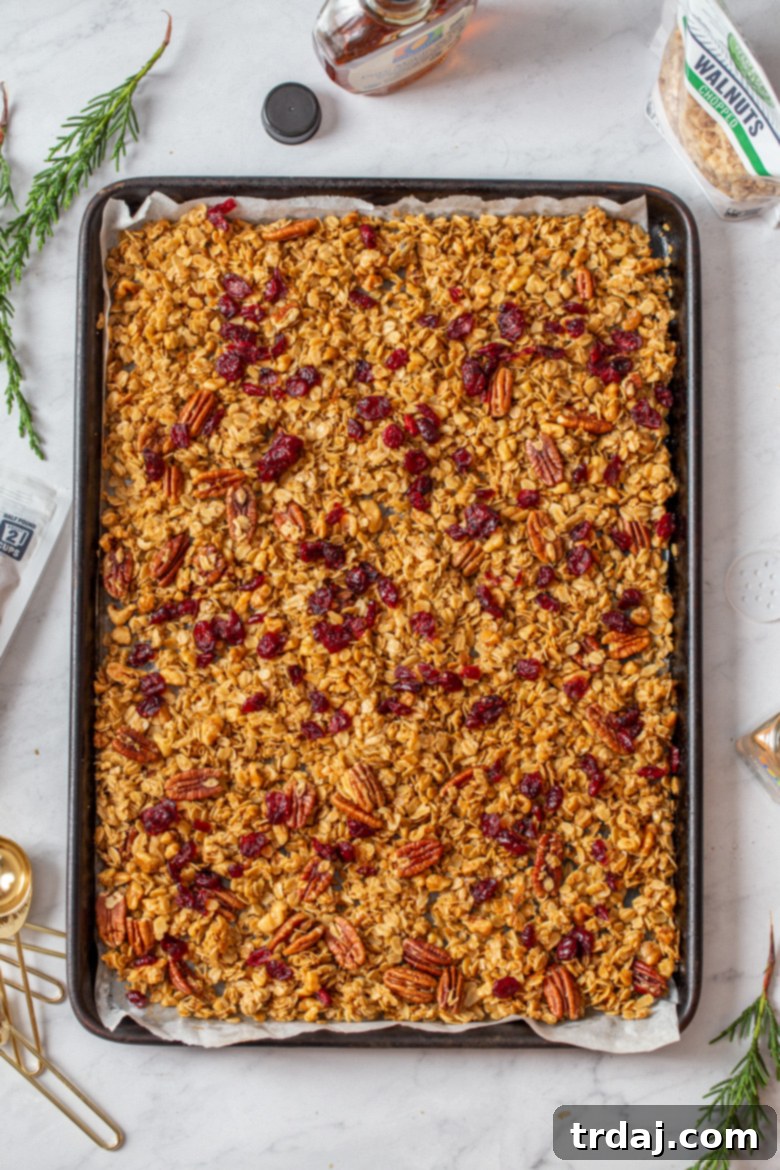 Adding dried cranberries to baked granola after removing it from the oven