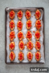 Decorating the cheese footballs with thin pimento strips to resemble the laces of a football, adding a festive touch.