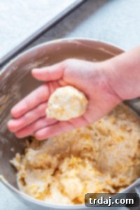 Scooping the cheese mixture into uniform 2-tablespoon-sized balls and shaping them into miniature footballs.