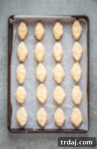 Arranging the freshly shaped cheese footballs onto a parchment-lined baking sheet before chilling.