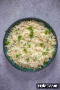 Cauliflower rice with cilantro and lime being prepared in a skillet.
