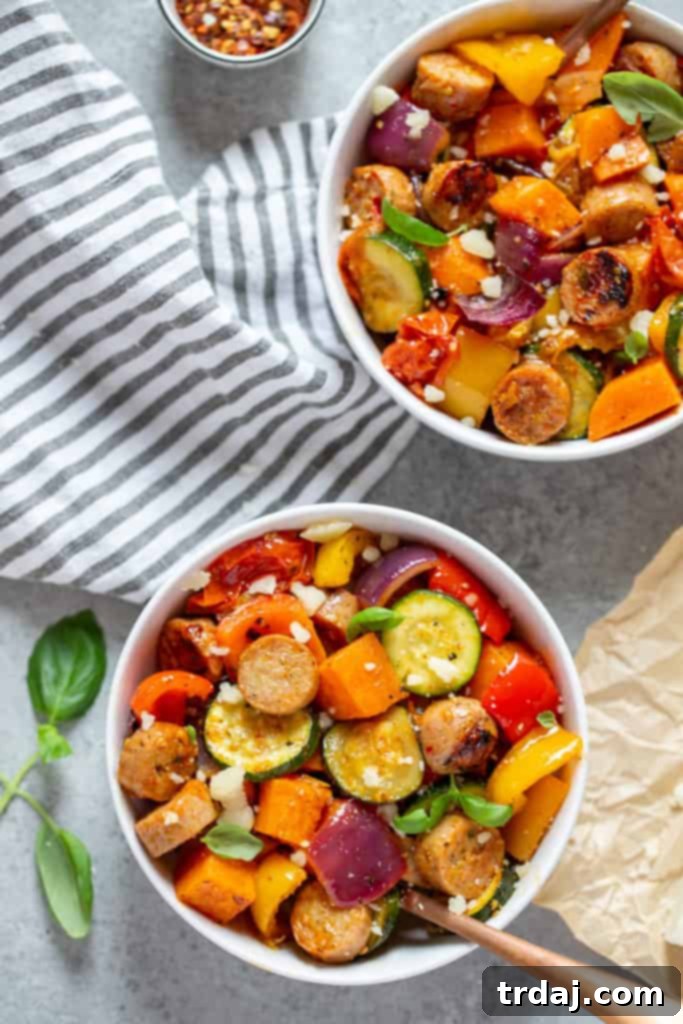 Vibrant bowls filled with perfectly oven-roasted chicken sausages and a colorful medley of vegetables, garnished with fresh basil and grated Parmesan cheese, ready to be enjoyed.