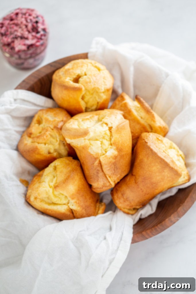 Golden brown popovers in a bowl, served with fresh blueberry basil butter
