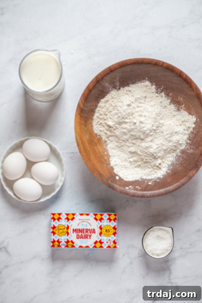 A collection of ingredients for popovers including milk, eggs, flour, salt, and Minerva Dairy butter on a wooden surface