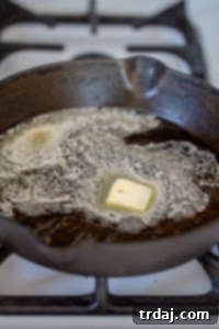 Diced vegetables sautéing in a cast iron skillet with butter