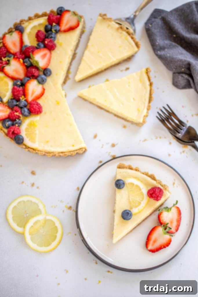 White Chocolate Lemon Cheesecake Tart displayed on a cake stand, garnished with fresh berries and lemon slices