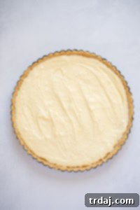 Cheesecake filling being poured into the pre-baked shortbread tart crust