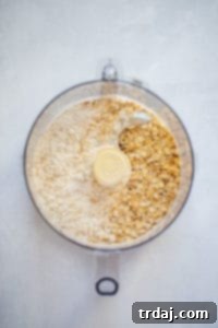 Softened butter being added to the dry ingredients for the crust in a food processor