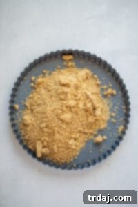 Crust crumbs being pressed into the bottom of a tart pan
