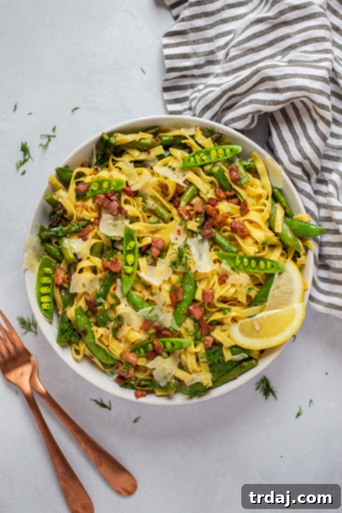 A close-up shot of the Springtime Lemon Pasta in a bowl, showcasing fresh asparagus, sugar snap peas, and dill.
