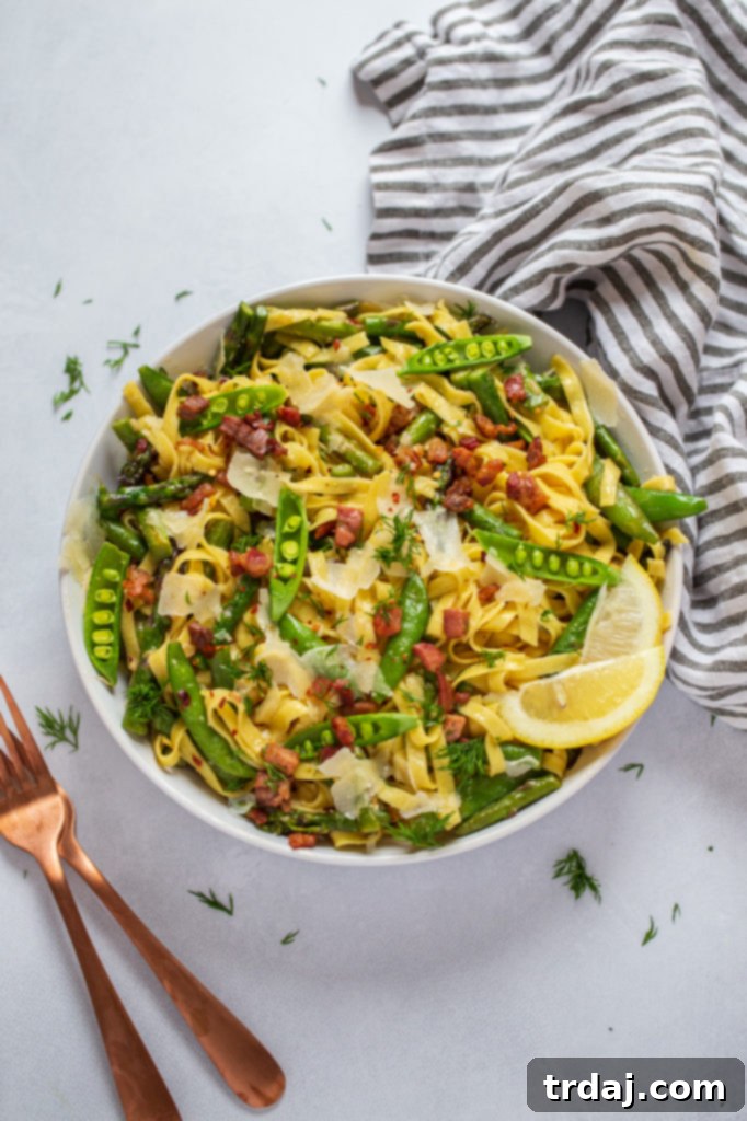 Springtime Lemon Pasta in a bowl, with a fork ready to pick up a mouthful. The dish is garnished with fresh dill.