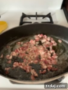 Crispy pancetta removed from the skillet, resting on a paper towel-lined plate.
