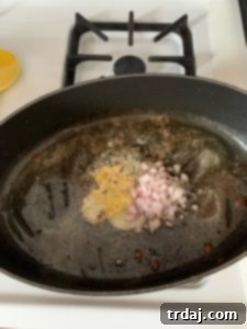 Minced garlic and diced shallots sautéing in melted butter in a skillet.
