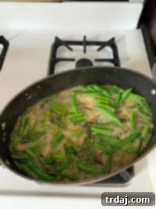 Asparagus and sugar snap peas added to the skillet with aromatics and pasta water.