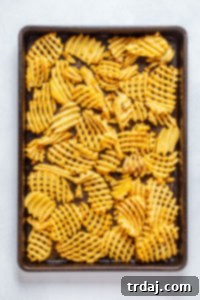 Frozen waffle fries spread on a baking sheet