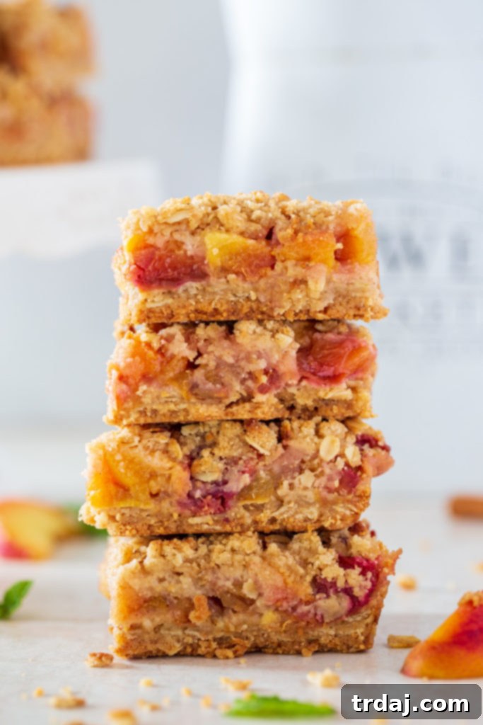 Close-up shot of four stacked peach cobbler oatmeal bars, showcasing the layers.