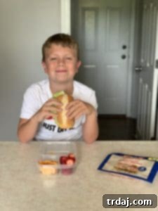 A close-up of a child's lunchbox with neatly packed food, including Land O'Frost deli meat roll-ups.